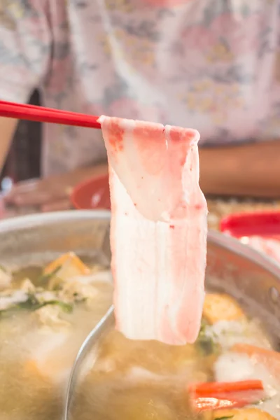 Červená hůlky drží na plátky vepřového sukiyaki — Stock fotografie