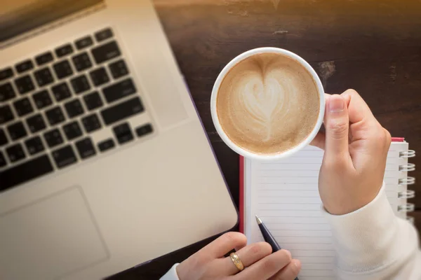 Mão na xícara de café na mesa de trabalho — Fotografia de Stock