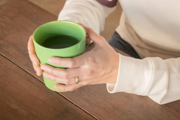 Kvinna hand på varmt grönt te dricker — Stockfoto