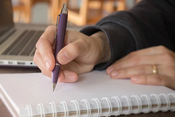 Kvinna hand skriva på noteboook papper — Stockfoto