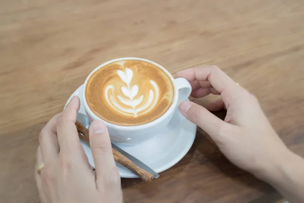 Mano en la taza caliente de café con leche —  Fotos de Stock