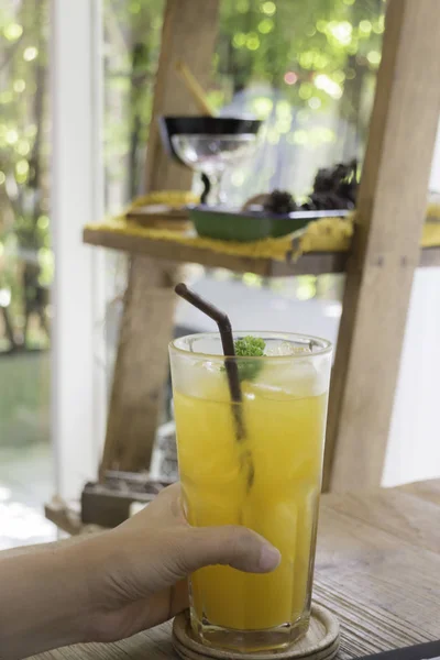 Woman hand on orange juice at table — Stock Photo, Image