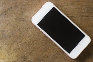 Ahşap masadaki boş ekranlı akıllı telefon