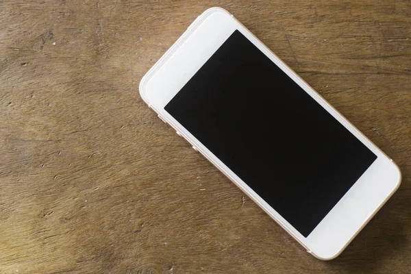 Smartphone mit leerem Bildschirm auf Holztisch — Stockfoto