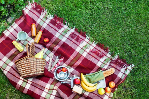 Cestino impostazione frutta cibo scacchi plaid erba picnic — Foto Stock