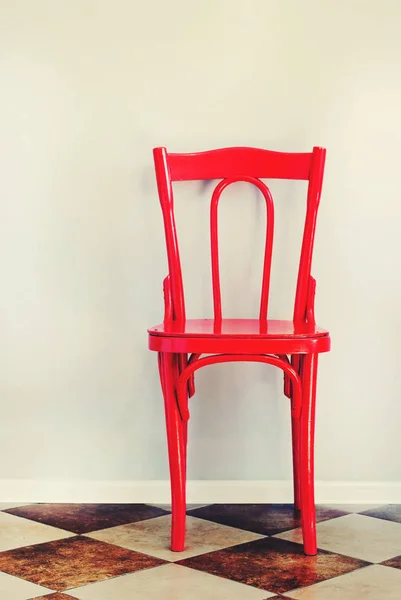 Czerwone krzesło płytki na podłodze w pobliżu beżowej ściany wewnątrz — Zdjęcie stockowe
