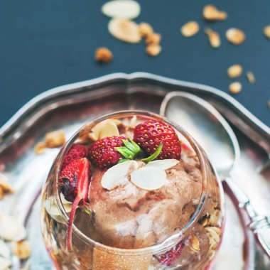 Çikolatalı dondurma cam bardak çilek dağınık müsli zararlı gıda koyu arka plan tonda dekore edilmiştir.