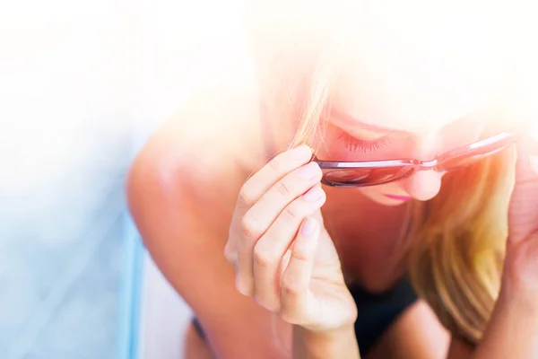 Улыбающаяся молодая загорелая женщина в солнечных очках — стоковое фото