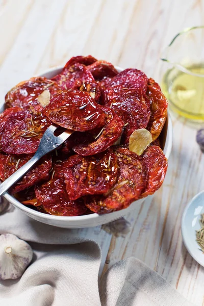 Los tomates secos con el ajo en la escudilla sobre blanco —  Fotos de Stock