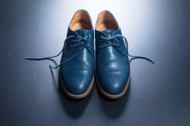 Koyu arkaplanda mavi erkek deri ayakkabıları.