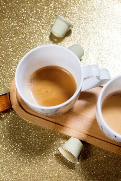 Zwei Tassen Espresso-Kaffee und Kapseln auf Gold — Stockfoto