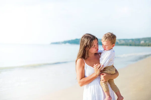 Young family in white clothes travel in Thailand and have a lot of fun. Beautiful mother and son on beach during summer vacation