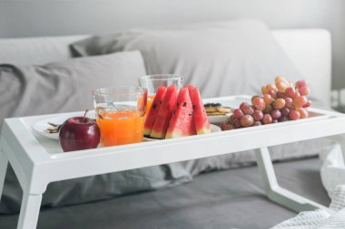 Yatakta sabah kahvaltısı. Beyaz tepsi portakal suyu dilimlenmiş karpuz ve otel odasının iç tarafındaki yastık kılıfında çikolata kaplı krep. Boşluğu kopyala