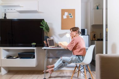 Kadın evde oturup uzaktan kumandayla çalışıyor. Karantina sırasında çalışan iş kadını. Kendini soyutlama. Ağ kurmak. Online eğitim. Coronavirus. Kriz. Araştırma.