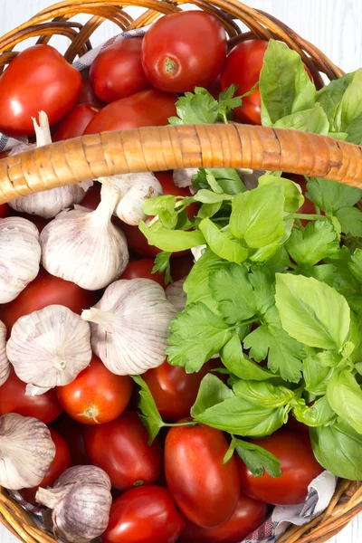 Tomates rojos, albahaca y ajo apilados a la cesta — Foto de Stock