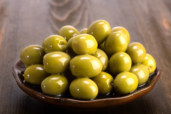 Green olives in oil stacked on a ceramic plate — Stock Photo, Image