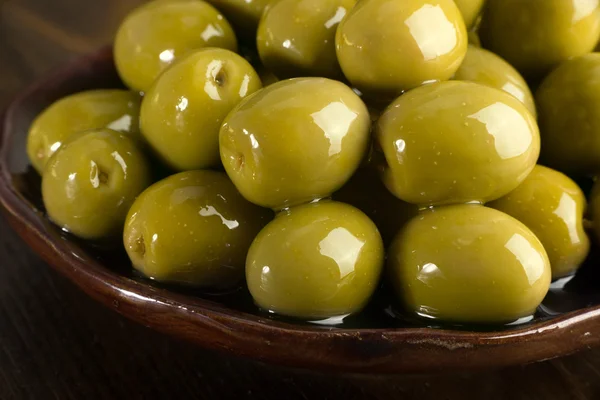Aceitunas verdes en aceite apiladas en una placa de cerámica — Foto de Stock