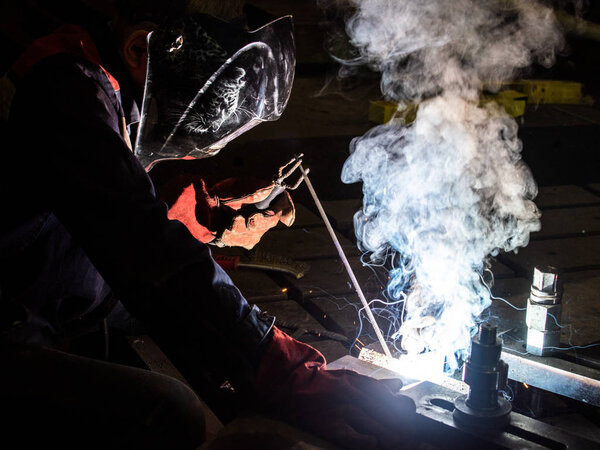 worker welds metal structures by electric arc welding