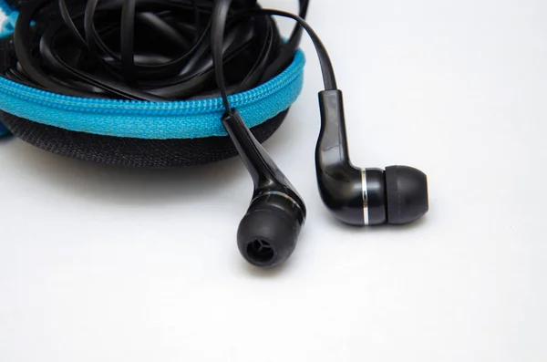 Portatif cihazlarda müzik ve ses dinlemek için siyah kulaklıklar: müzik çalar, akıllı telefon, dizüstü bilgisayar ve beyaz arka planda bağlantı için kriko. Kulak tıkaçları.