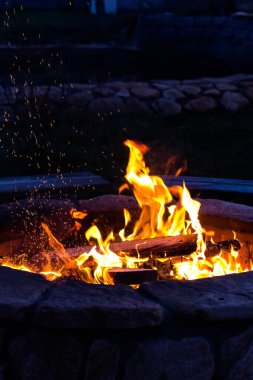 Ateş ve gece kıvılcımları. Parlak alevler ve gökyüzüne yükselen kıvılcımlar. Şehirden uzakta bir hayat. Koyu arkaplanda ateşin dokusu