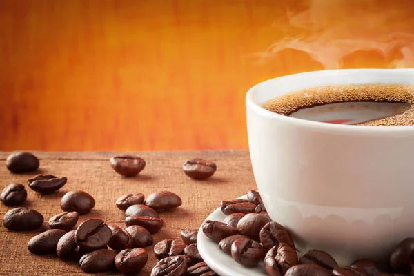Xícara de café em uma mesa de madeira com grãos de café — Fotografia de Stock