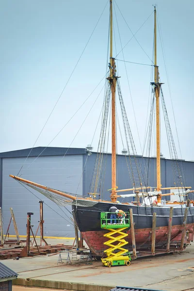 Sail boat with workers in a boatyard being repaired and restored — Stock Image Sail boat with workers in a boatyard being repaired and restored Royalty Free Stock Photos