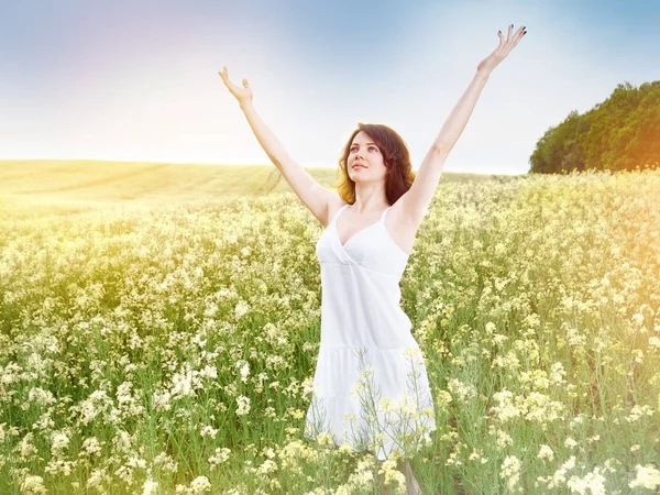 Kvinna i fältet med gula blommor på sommar solnedgång. — Stockfoto