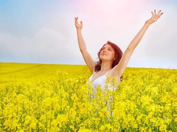 Frau im Feld mit gelben Blumen bei Sonnenuntergang im Sommer. — Stockfoto