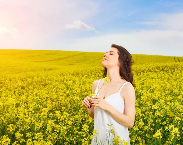 Frau im Feld mit gelben Blumen bei Sonnenuntergang im Sommer. — Stockfoto
