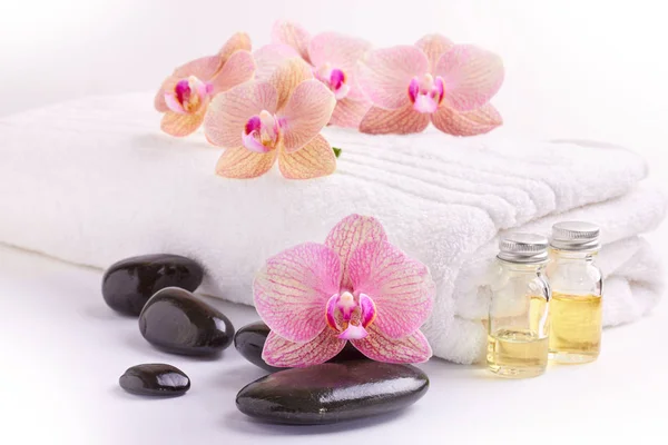 Rosa orkidéer, mjukgörande oljor och spa stenar på vitt — Stockfoto