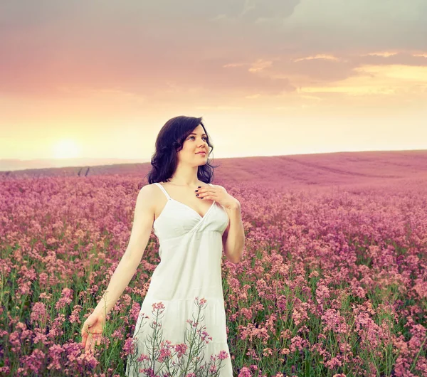 Frau im Feld mit Blumen bei Sonnenuntergang — Stockfoto