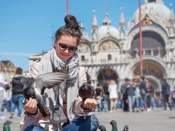 Joven viajera sentada y alimentando palomas en la Piazza San Marco — Foto de Stock