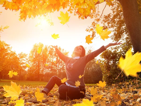 Szczęśliwa kobieta kropla się liści w parku jesień — Zdjęcie stockowe