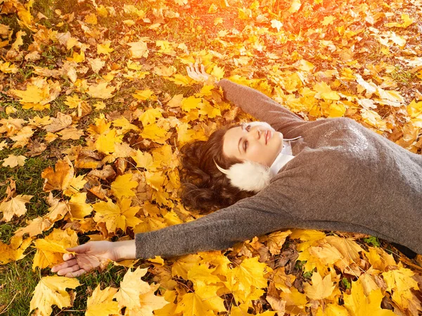Kobieta, leżąc na żółte listowie i cieszyć się dzień jesieni, widok z góry — Zdjęcie stockowe