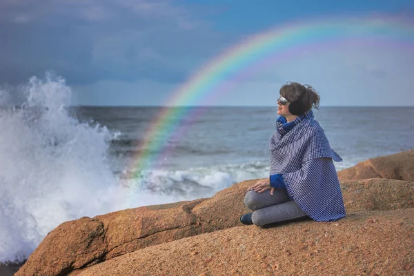 Kvinna på steniga stranden, regnbåge över stormigt hav — Stockfoto