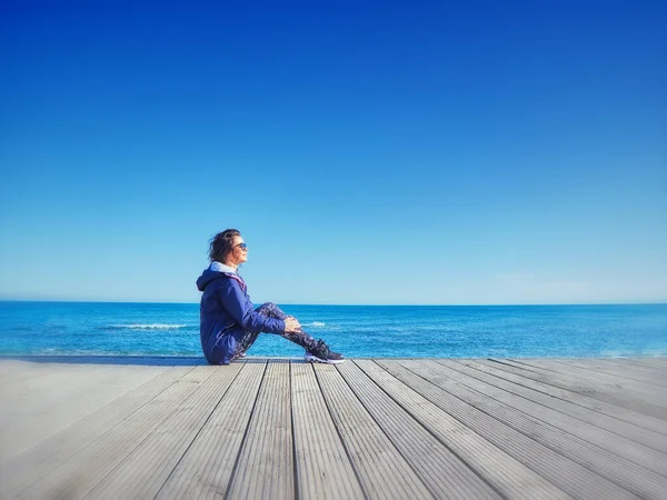 Mujer en un muelle de madera. Fondo de mar y cielo . — Foto de Stock