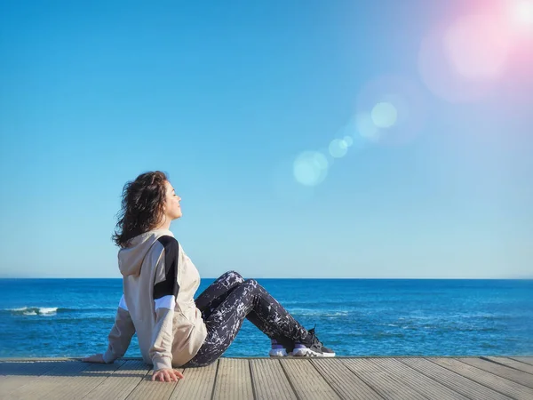 Donna su un molo di legno. Sfondo spiaggia. Yoga, sport, vacanza e libertà concetto . — Foto Stock