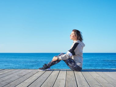 Ahşap iskelede bir kadın. Yoga, spor, tatil ve özgürlük kavramı.