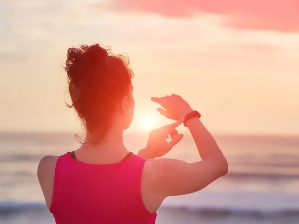 Donna guardando cardiofrequenzimetro guardare fuori facendo jogging sulla spiaggia . — Foto Stock