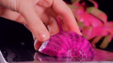 Siyah arka planda sulu taze Pitahaya Ejderha Meyvesi kesiyorum..