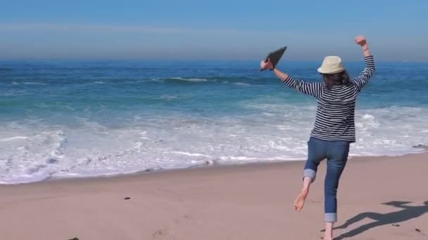 Mujer feliz con portátil recibiendo buenas noticias en la playa . — Vídeos de Stock