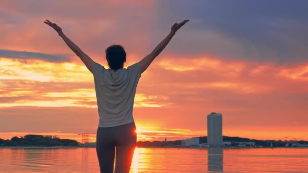 Caucasian woman in sport clothes raising arms to the sky at sunset — Stock Video