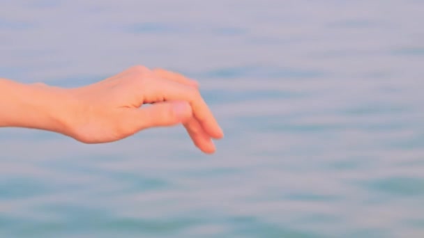A női kéz a tengervíz ellen hullámzik. Nyári szabadság koncepciója — Stock videók