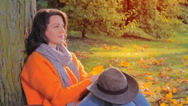 Hermosa mujer con hojas de otoño en el fondo del parque de otoño — Vídeo de stock