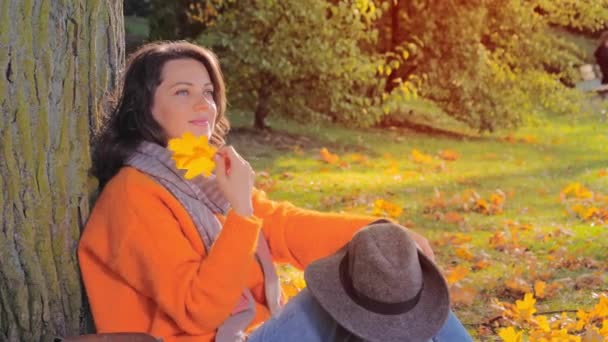 Прекрасна осінь жінка з апельсиновим листям в парку — стокове відео