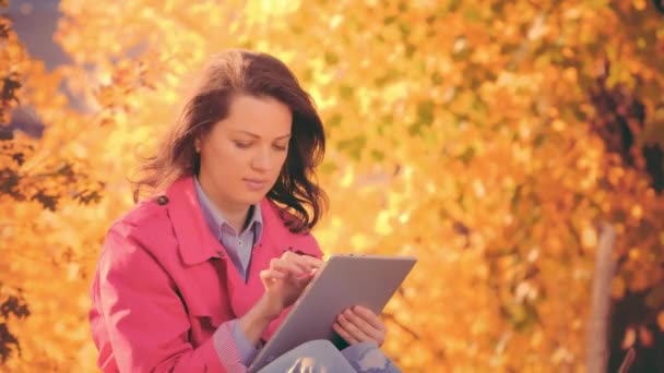 Mulher de manto vermelho trabalhando com seu tablet, horário de outono — Vídeo de Stock