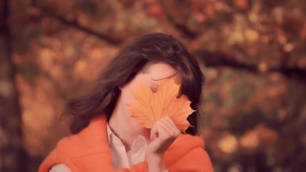 Giovane donna sorridente con foglia giallo autunno, concetto di autunno — Video Stock