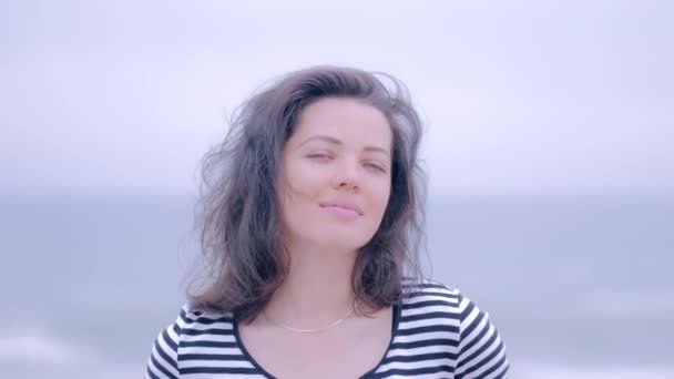 Portrait of a blue eyed woman on striped shirt on a rainy beach — 비디오