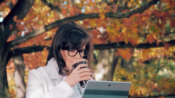 Mujer bebiendo café y trabajando con su cuaderno afuera — Vídeos de Stock