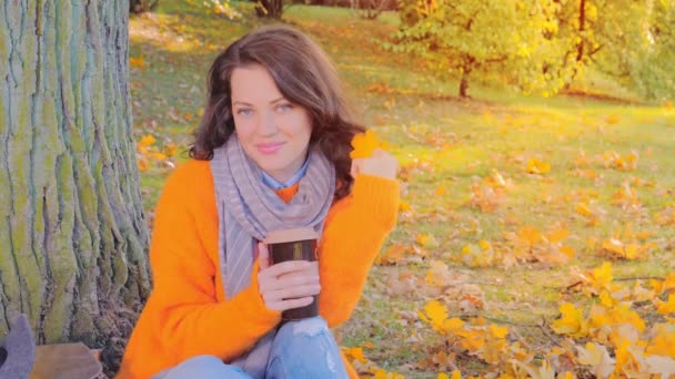 Όμορφη γυναίκα σε μάλλινο πουλόβερ πίνοντας τσάι στον κήπο φθινόπωρο — Αρχείο Βίντεο